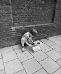 859492 Afbeelding van een kind bij een knikkerpotje in het trottoir van de Pelmolenweg te Utrecht.